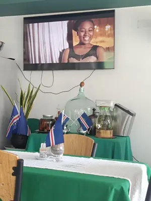 a table with a green table cloth and a tv on the wall at Apartamento Praia JOIA in Praia