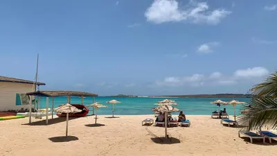 a beach with umbrellas and people sitting on the sand at Beautiful Penthouse in Sal Rei