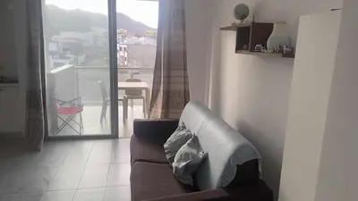 a living room with a couch in front of a window at Apartamento T1 - Hotel Las Rochas in Mindelo