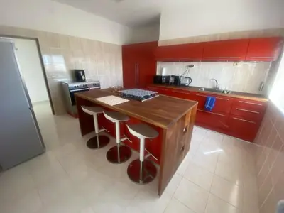 a kitchen with red cabinets and a wooden island with stools at Casa Ramanda in Tarrafal