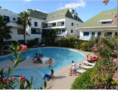 a group of people in a swimming pool in front of a building at Leme Bedje Residence in Santa Maria
