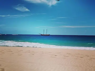 a boat sitting in the ocean on a beach at Leme Bedje Residence in Santa Maria