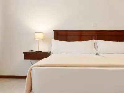 a white bed with a wooden headboard and a lamp at Aaparthotel Book a Taxi Group in Prainha
