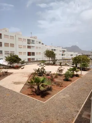 a building with a courtyard with trees and buildings at Vila Kola Sanjon in Mindelo