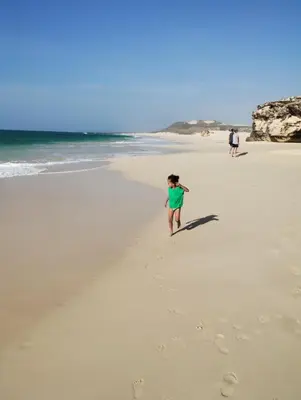 a woman walking on a beach with footprints in the sand at Boadream Casa Duria Porta Viola in Prainha