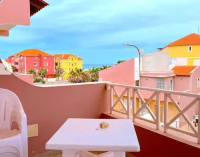 a small white table on a balcony with buildings at Holiday Properties Prestige Apartments in Santa Maria