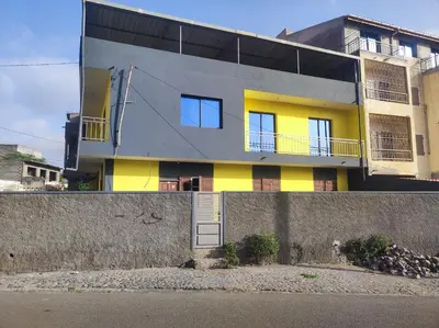 a yellow and grey house with a wall at Kaza Horta in Tarrafal