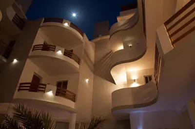 a large white building with balconies at night at Cala da Lua apartments in Sal Rei