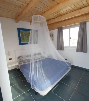 a bed with a mosquito net in a room at Cala da Lua apartments in Sal Rei
