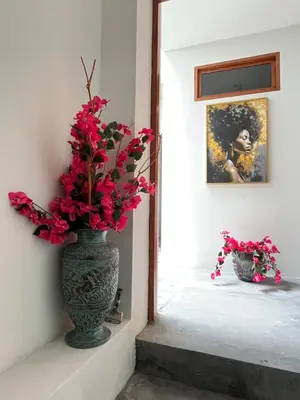 a vase with red flowers sitting on a wall at Boutique Hotel Luz da Lua in Ponta do Sol