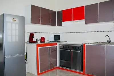 a kitchen with red cabinets and stainless steel appliances at La Kaza du Soleil in Tarrafal