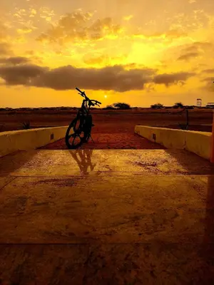 a bike parked on a ledge with the sunset in the background at Alma MIRIAM in Sal Rei