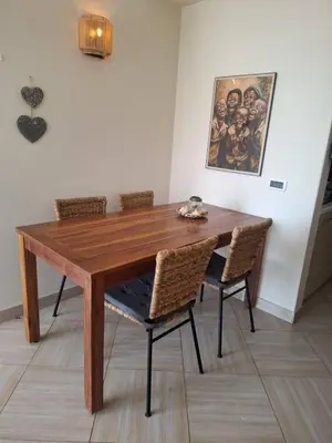a wooden dining room table with chairs and a painting at Lovely Seaview Apartment Magnolia in Santa Maria