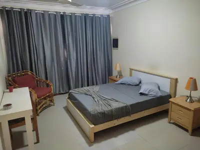 a bedroom with a bed and a chair and a window at Apartamentos Sossego in Praia