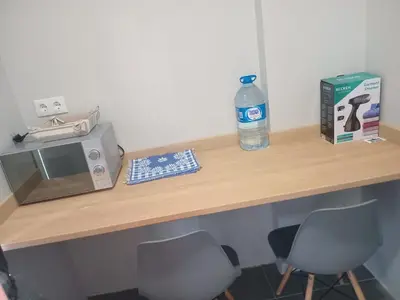 a table with a microwave and a bottle of water on it at Abraço d Mindel in Mindelo