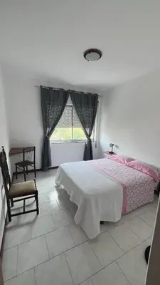 a bedroom with a bed and a chair and a window at Casa Fortes in Praia