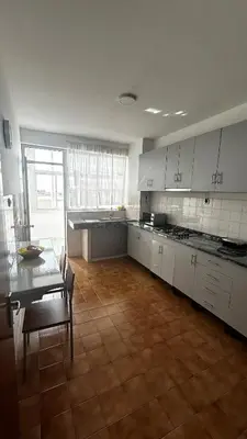 a large kitchen with white cabinets and a wooden floor at Casa Fortes in Praia