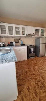 a kitchen with white cabinets and a wooden floor at Morabeza Serena in Santa Maria