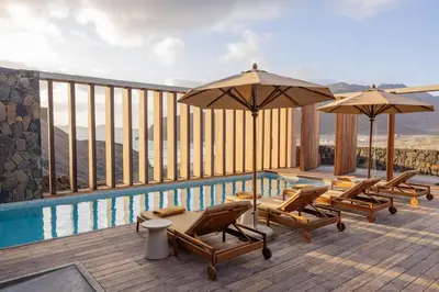 a deck with chairs and umbrellas next to a pool at Villa - Vue Mer et Piscine Privée in Mindelo