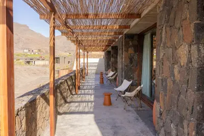 a stone building with a porch with chairs and a roof at Villa - Vue Mer et Piscine Privée in Mindelo