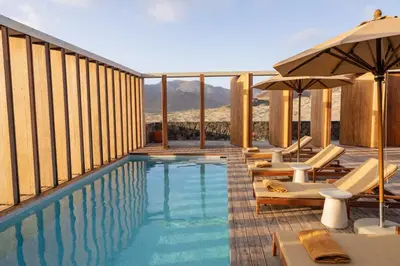 a swimming pool with chairs and umbrellas on a building at Villa - Vue Mer et Piscine Privée in Mindelo