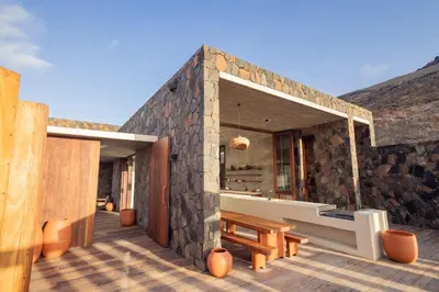 a stone building with a bench on a wooden deck at Villa - Vue Mer et Piscine Privée in Mindelo