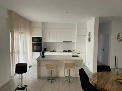 a kitchen with white cabinets and a table with chairs at Grace apartamento T2 in Praia