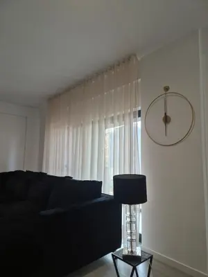 a living room with a black couch and a window at Grace apartamento T2 in Praia