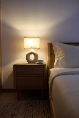 a lamp on a night stand next to a bed at Bordão Apartments in Praia