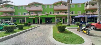 a scooter parked in front of a green building at Sal service green moradias residence with pool in Santa Maria