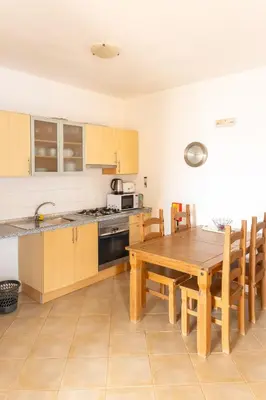 a kitchen with a wooden table and wooden chairs at Santa Maria Residence in Santa Maria