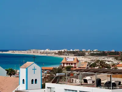 a white church with a cross on the side of a beach at Albis Harena - In Sal in Santa Maria