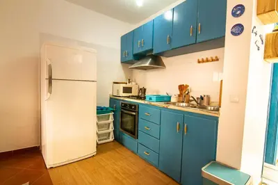 a kitchen with blue cabinets and a white refrigerator at Casinha Azul Cidade Velha - Blue House Old Town in Cidade Velha
