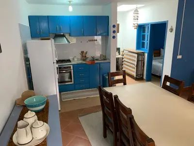 a kitchen with blue cabinets and a table and chairs at Casinha Azul Cidade Velha - Blue House Old Town in Cidade Velha