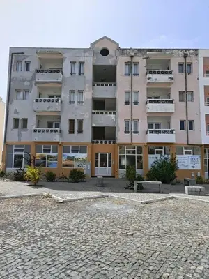 a large apartment building with a cobblestone parking lot at Girassol Tarrafal Apartment in Tarrafal