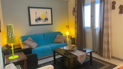 a living room with a blue couch and a table at Girassol Tarrafal Apartment in Tarrafal