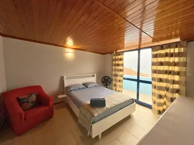 a bedroom with a bed and a red chair at Residencial Alto do Fortim in Mindelo