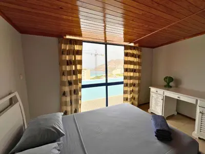 a bedroom with a bed and a view of a pool at Residencial Alto do Fortim in Mindelo