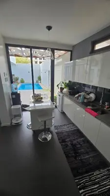 a kitchen with white cabinets and a table in it at Family apartment with pool in Praia