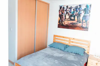 a bedroom with a bed with a painting on the wall at Palmarejo, Apartamento T2 no Prédio Rosa Trás de pão quente in Praia
