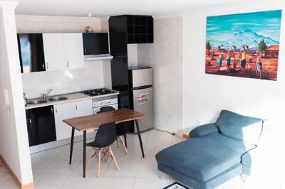 a kitchen with a wooden table and a blue chair at Palmarejo, Apartamento T2 no Prédio Rosa Trás de pão quente in Praia