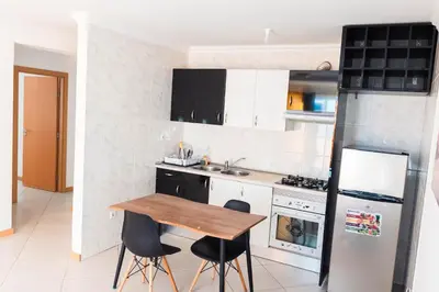 a kitchen with a wooden table and two chairs at Palmarejo, Apartamento T2 no Prédio Rosa Trás de pão quente in Praia