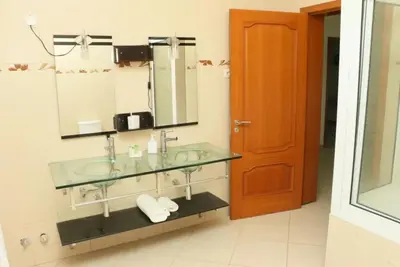 a bathroom with a glass sink and a mirror at Cidade Serena in Cidade Velha