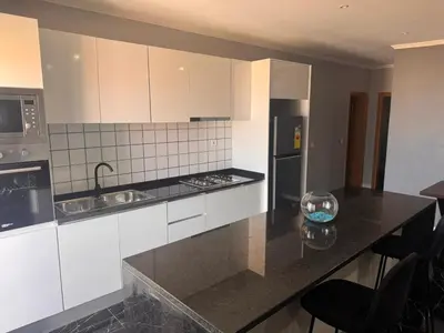 a kitchen with white cabinets and a black counter top at Apartamento mais Carro George Mendes in Praia