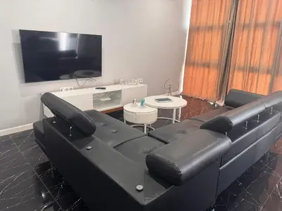 a living room with a black couch and a tv at Apartamento mais Carro George Mendes in Praia