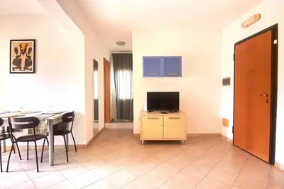 a living room with a television and a table with chairs at Sea Breeze Apartment in Santa Maria