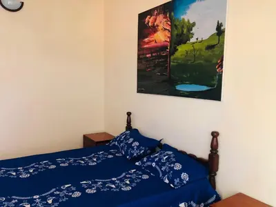 a bedroom with a bed with blue sheets and a painting at PJ t1 conforto e paz 4E in Praia