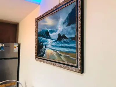 a painting hanging on a wall next to a refrigerator at PJ t1 conforto e paz 4E in Praia