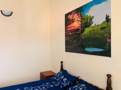 a bedroom with a painting hanging above a bed at PJ t1 conforto e paz 4E in Praia