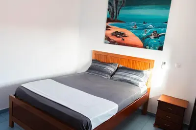 a bedroom with a bed with a painting on the wall at Palmarejo, Apartamento T1, frente Praça Center in Praia